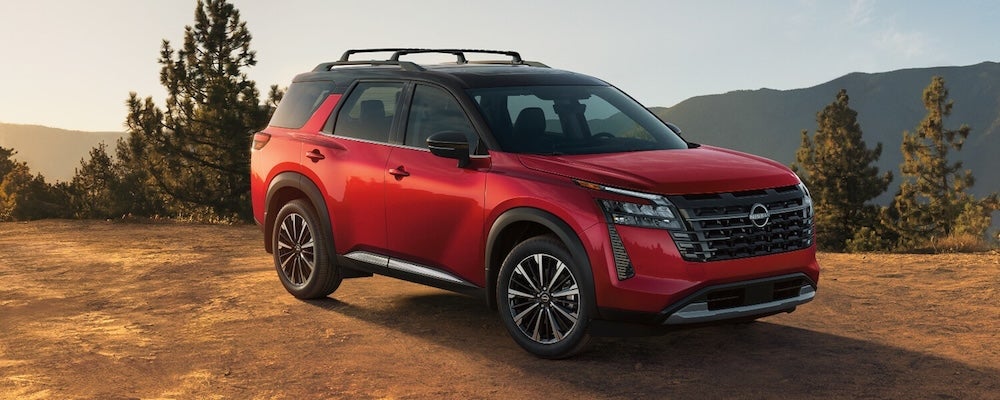 A red 2026 Nissan Rogue SUV parked on a dirt mountain ledge