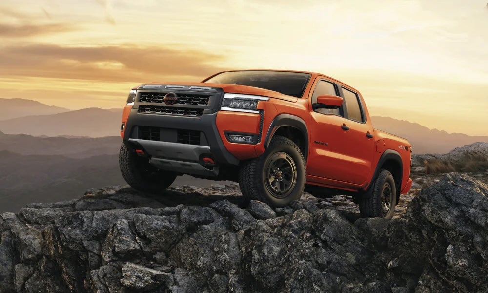An orange 2026 Nissan Frontier truck parked on a rock ledge