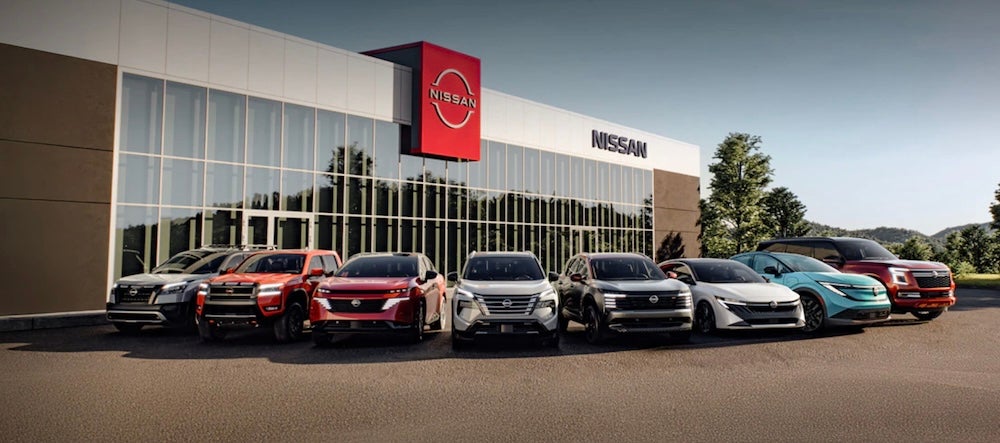 Several Nissan vehicles parked in front of a Nissan dealership